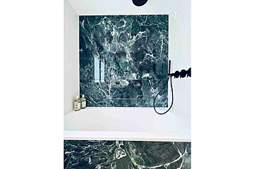 A bathroom with green marble walls and a bathtub