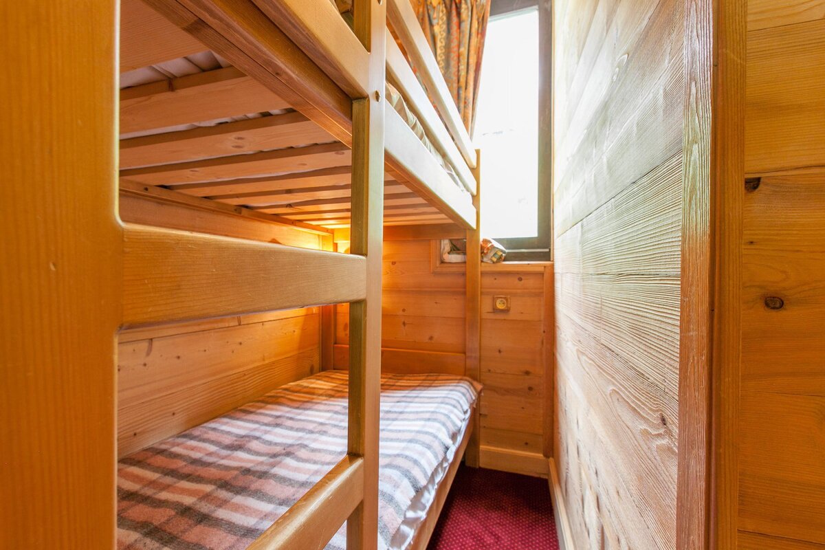 A wooden bunk bed with a window in the background