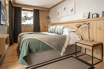A bedroom with a bed a nightstand and a lamp