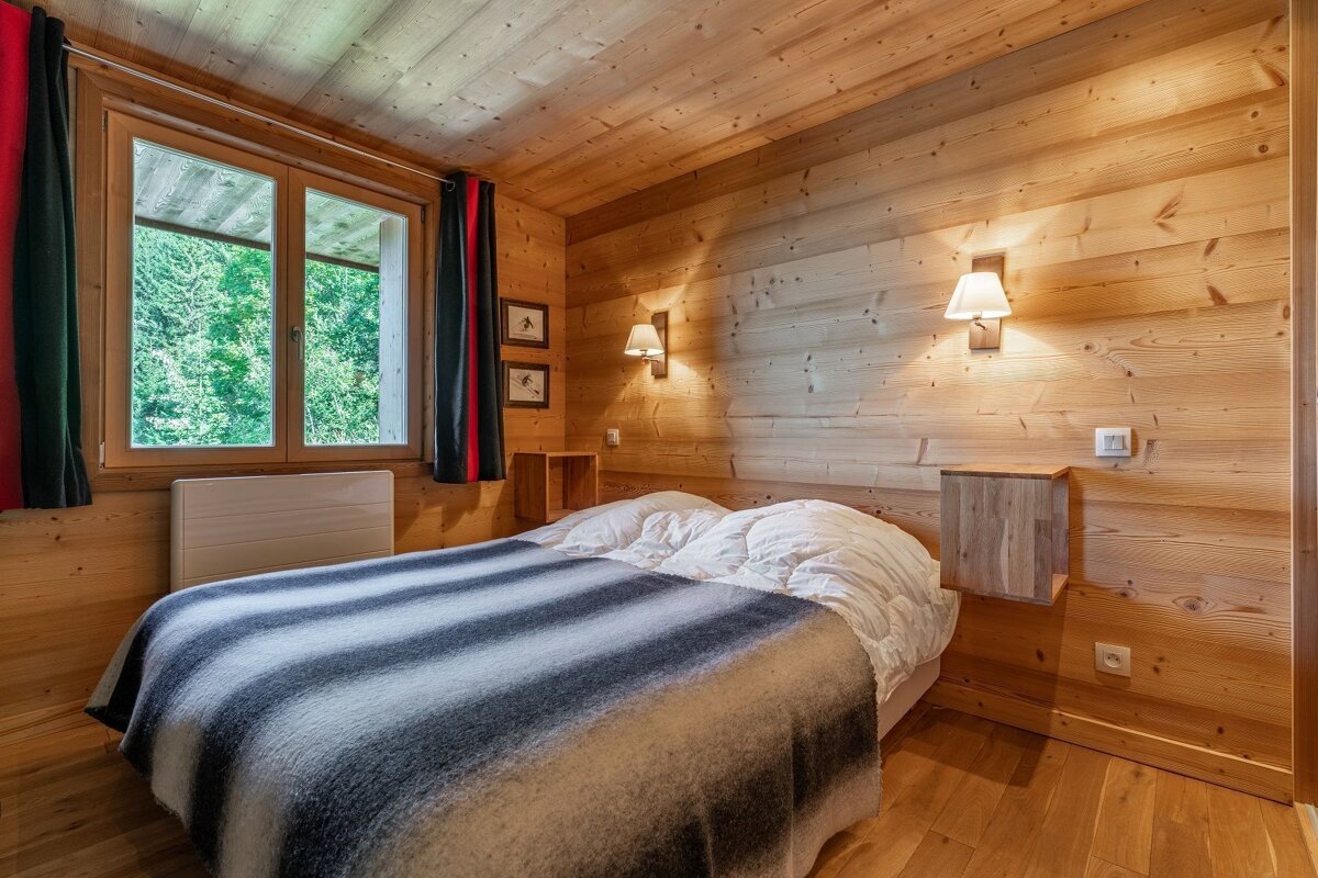 A wooden bedroom with a bed and a window