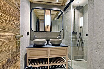 A bathroom with two sinks and a walk in shower