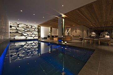 A large indoor swimming pool with a stone wall behind it