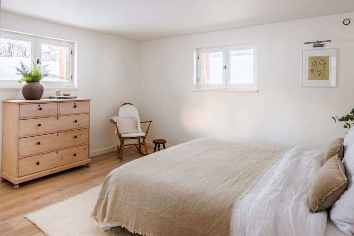 A bedroom with a bed a dresser and a rocking chair