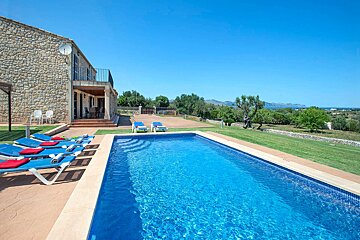 A large swimming pool in front of a stone house