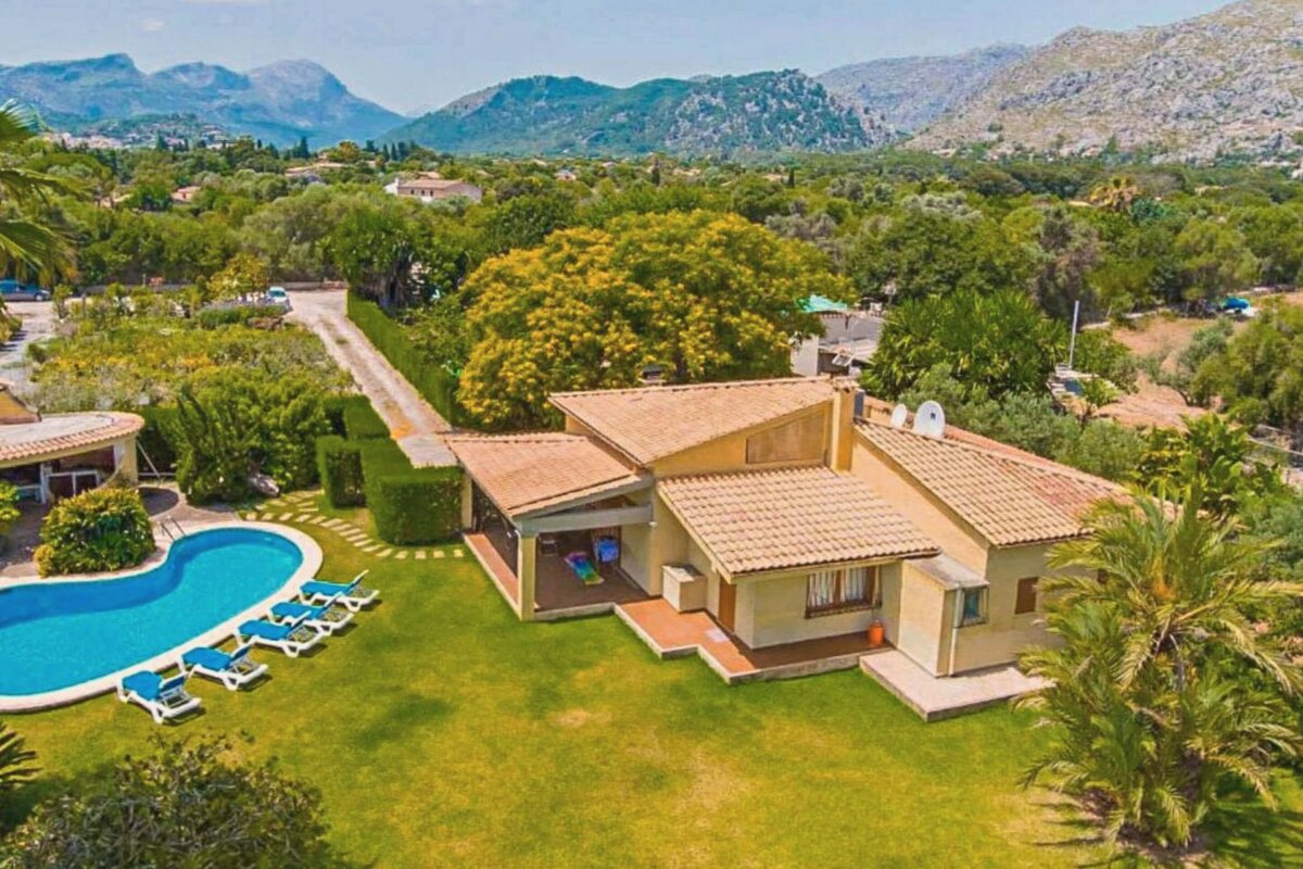 An aerial view of a house with a pool and mountains in the background