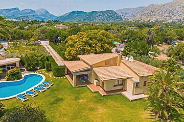 An aerial view of a house with a pool and mountains in the background