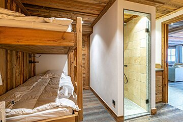 A bedroom with wooden walls and a bed with a white comforter