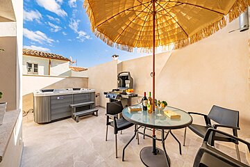 A patio with a table and chairs and a hot tub