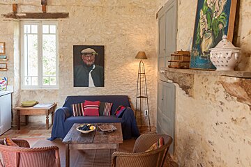 A living room with a blue couch and a painting on the wall