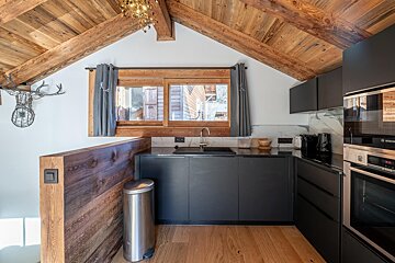 A bottle of wine sits on a wooden table in a kitchen