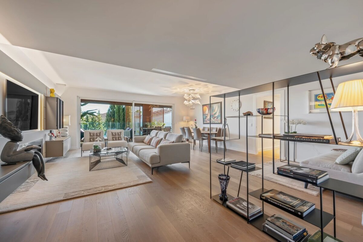 A spacious, modern open-plan living and dining area with hardwood floors, contemporary furniture, large windows, and stylish decor.