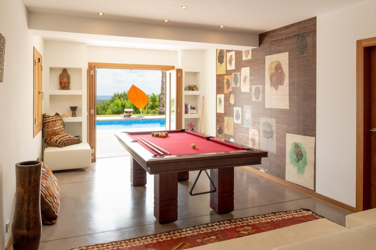 A pool table in a room with a pool in the background