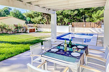 A table with a bottle of wine on it in front of a pool