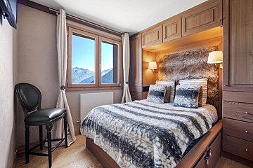 A bedroom with a large bed and a chair