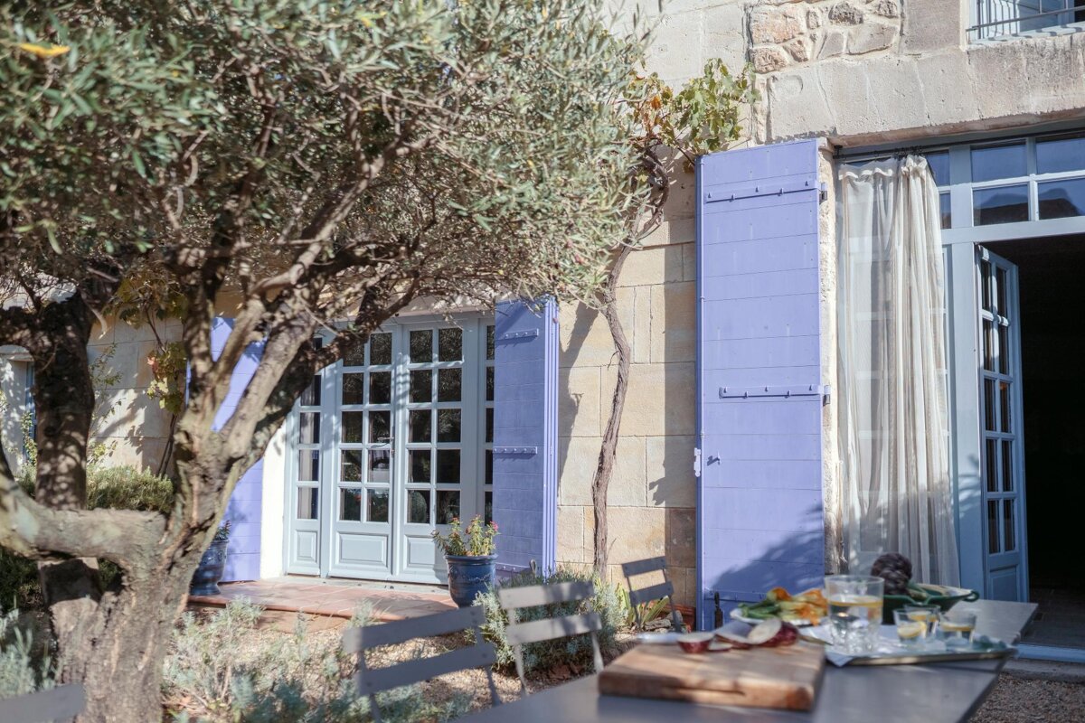 A table and chairs outside of a house with purple shutters