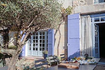 A table and chairs outside of a house with purple shutters