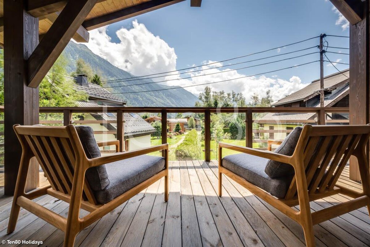 Two chairs on a balcony with mountains in the background