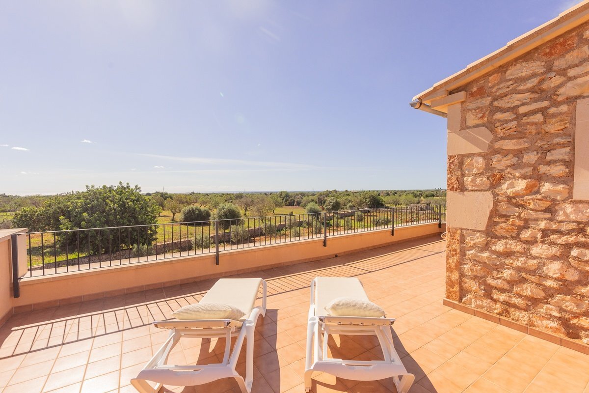 Two lounge chairs on a balcony with a view of trees