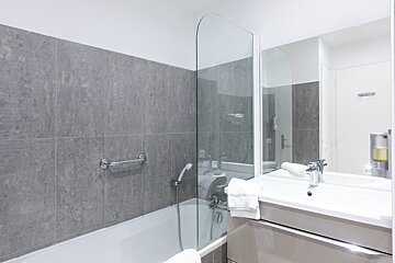 A bathroom with a bathtub a sink and a mirror
