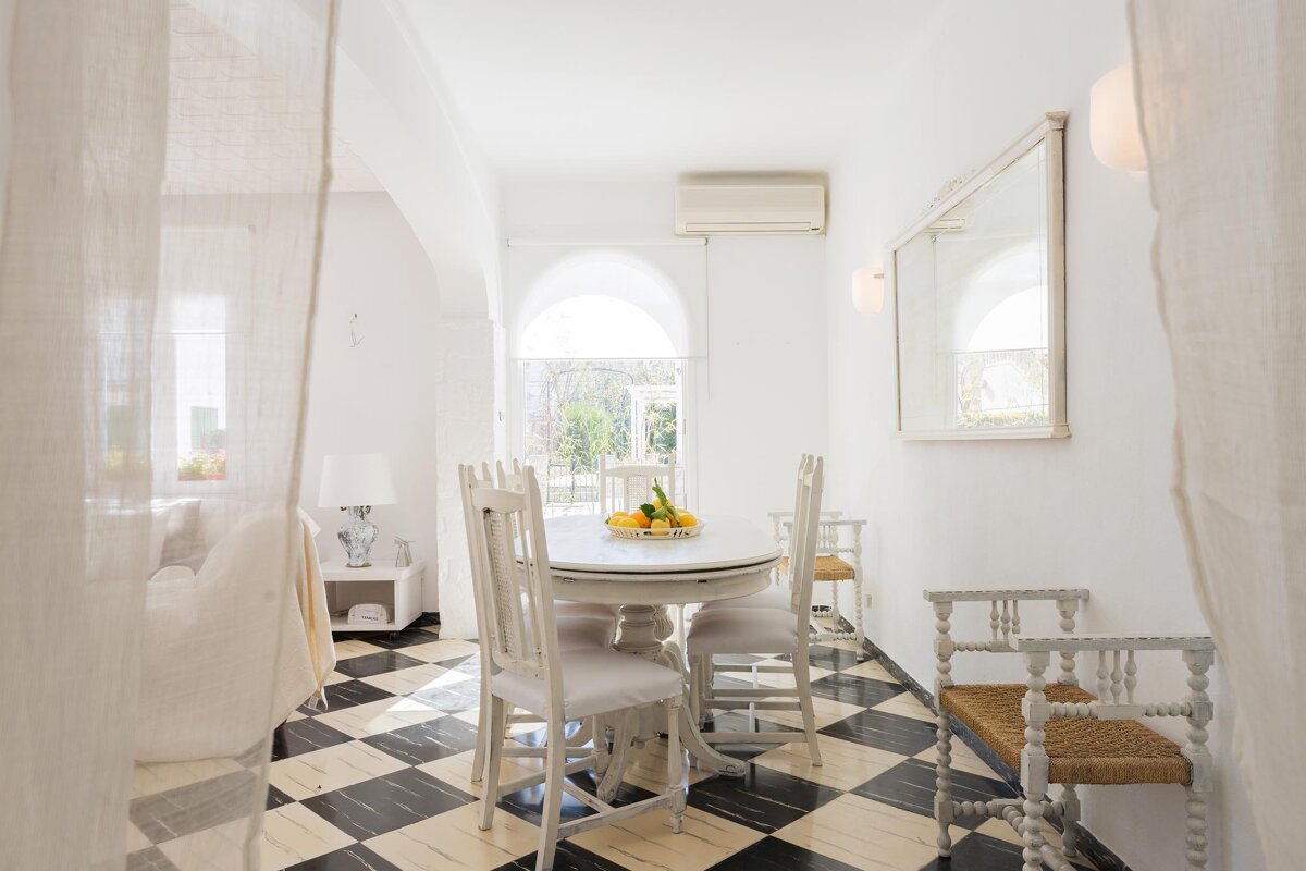 A dining room with a table and chairs and a mirror