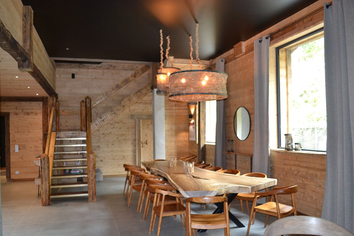 A dining room with a large wooden table and chairs