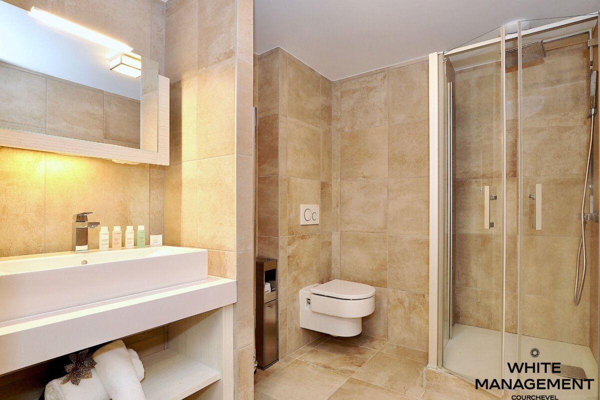 A bathroom with a rental designer logo on the bottom right