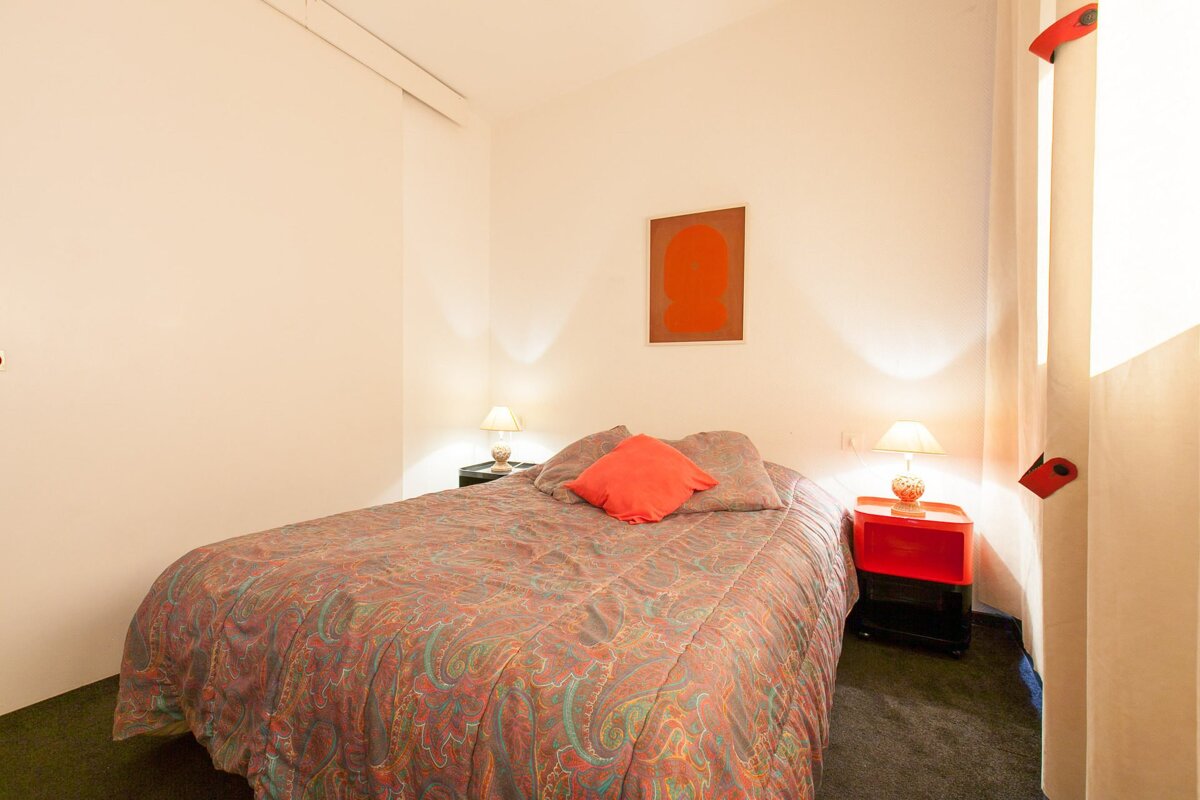 A small bedroom with a bed and two lamps