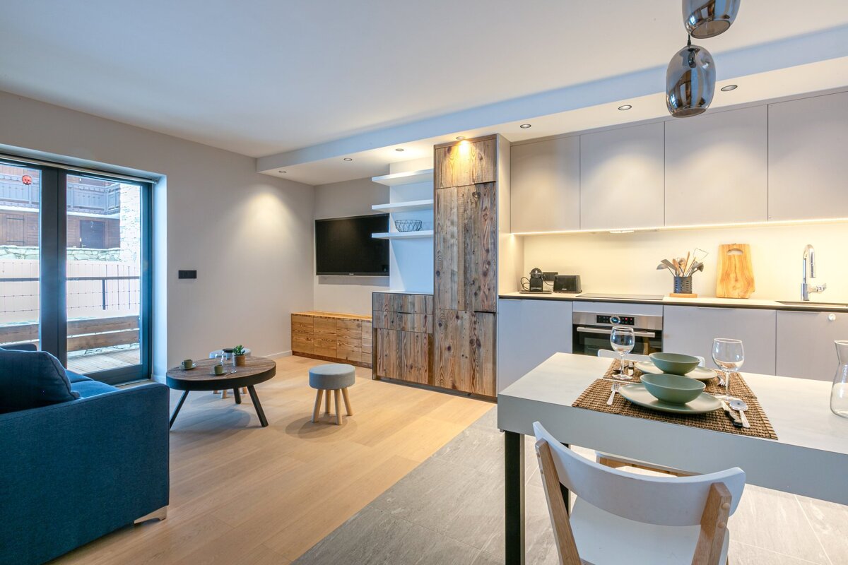 A living room with a table and chairs and a flat screen tv