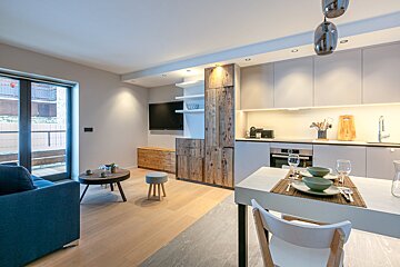 A living room with a table and chairs and a flat screen tv