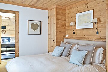 A bedroom with a bed and a heart shaped picture on the wall