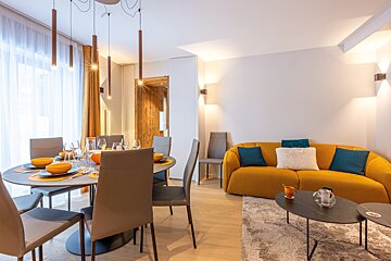 A living room with a yellow couch and a dining table