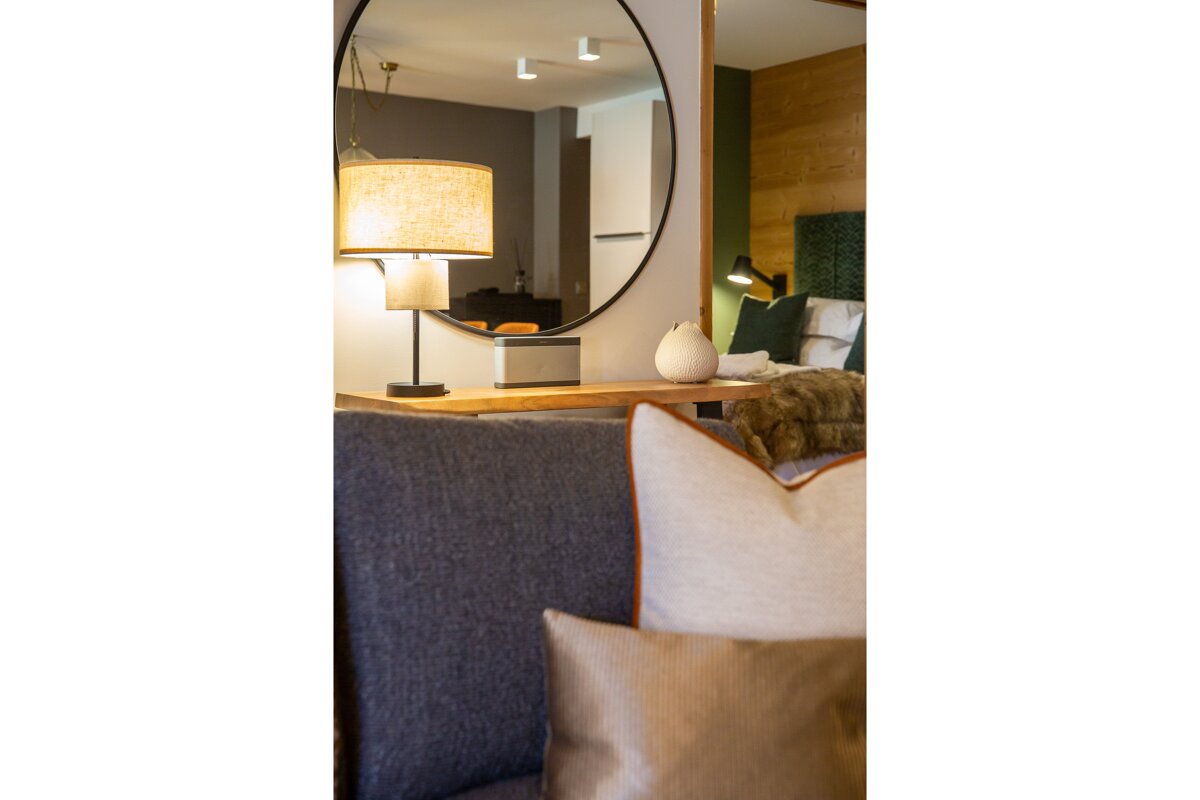 A living room with a round mirror and a lamp