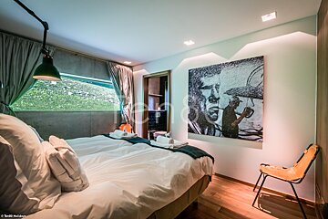 A bedroom with two beds and a painting on the wall