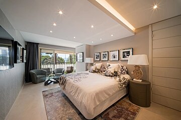 Elegant modern bedroom featuring a large bed, stylish decor, and a seating area near sliding doors leading to a balcony.