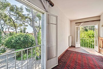 A room with a balcony and trees in the background