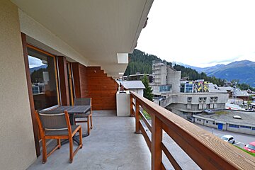 A balcony with a table and chairs and a view of mountains