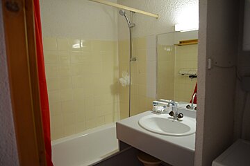A bathroom with a sink and a red curtain