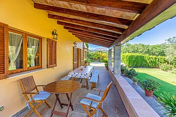 A porch with a table and chairs under a wooden roof