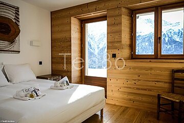 A bedroom with a bed and a window with the word tebo on the wall