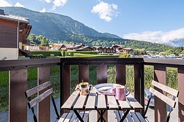 A balcony with a table and chairs and mountains in the background