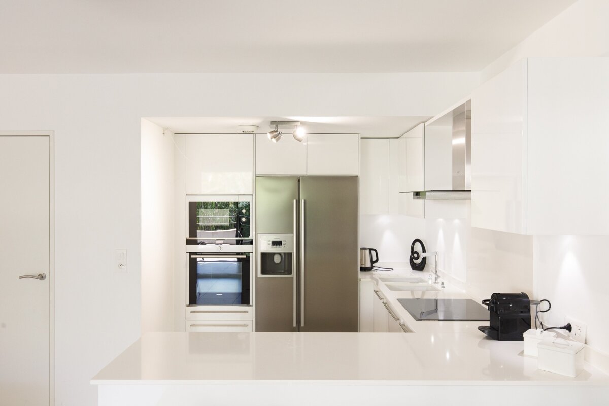 A kitchen with white cabinets and a stainless steel refrigerator