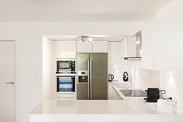 A kitchen with white cabinets and a stainless steel refrigerator
