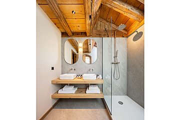 A bathroom with two sinks and a walk in shower