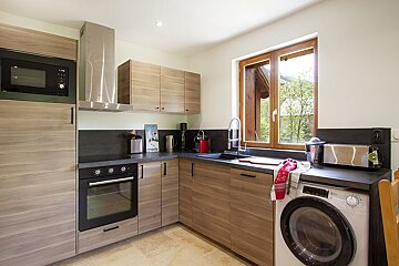 A kitchen with wooden cabinets and a washer and dryer