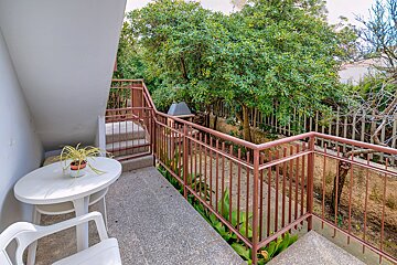A balcony with a table and chairs and a plant on it