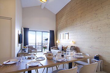 A dining room table with a bottle of wine on it