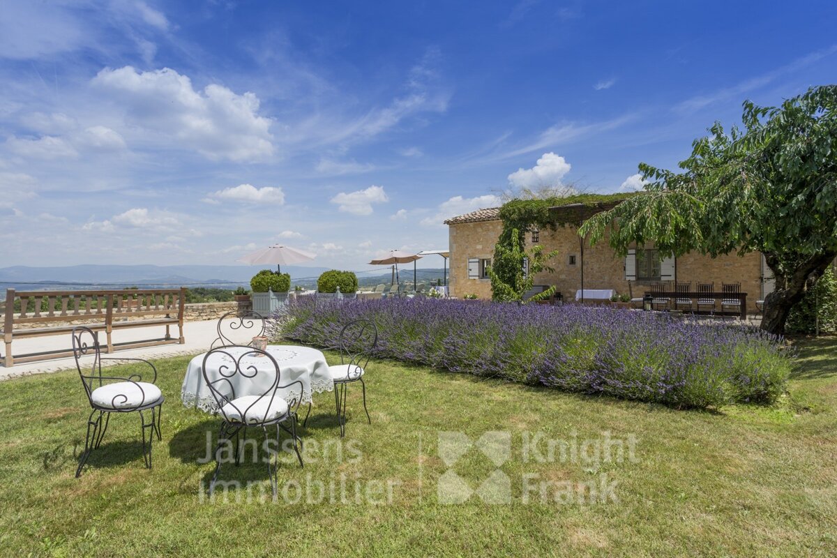 A lawn with a table and chairs and a sign that says janssens immobilier