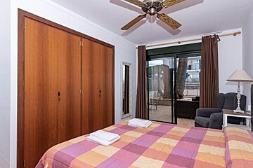 A bedroom with a large bed and a ceiling fan