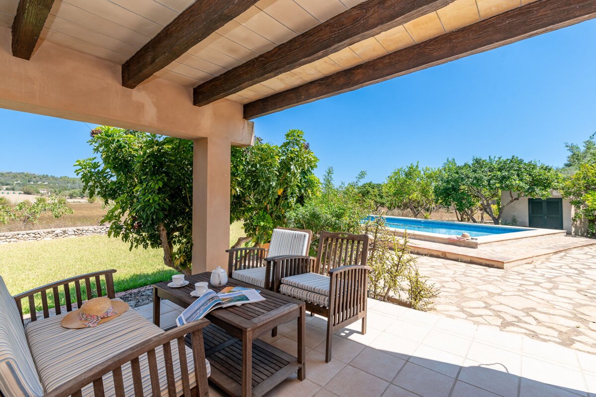 A patio with a table and chairs and a pool in the background