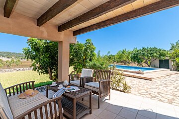A patio with a table and chairs and a pool in the background